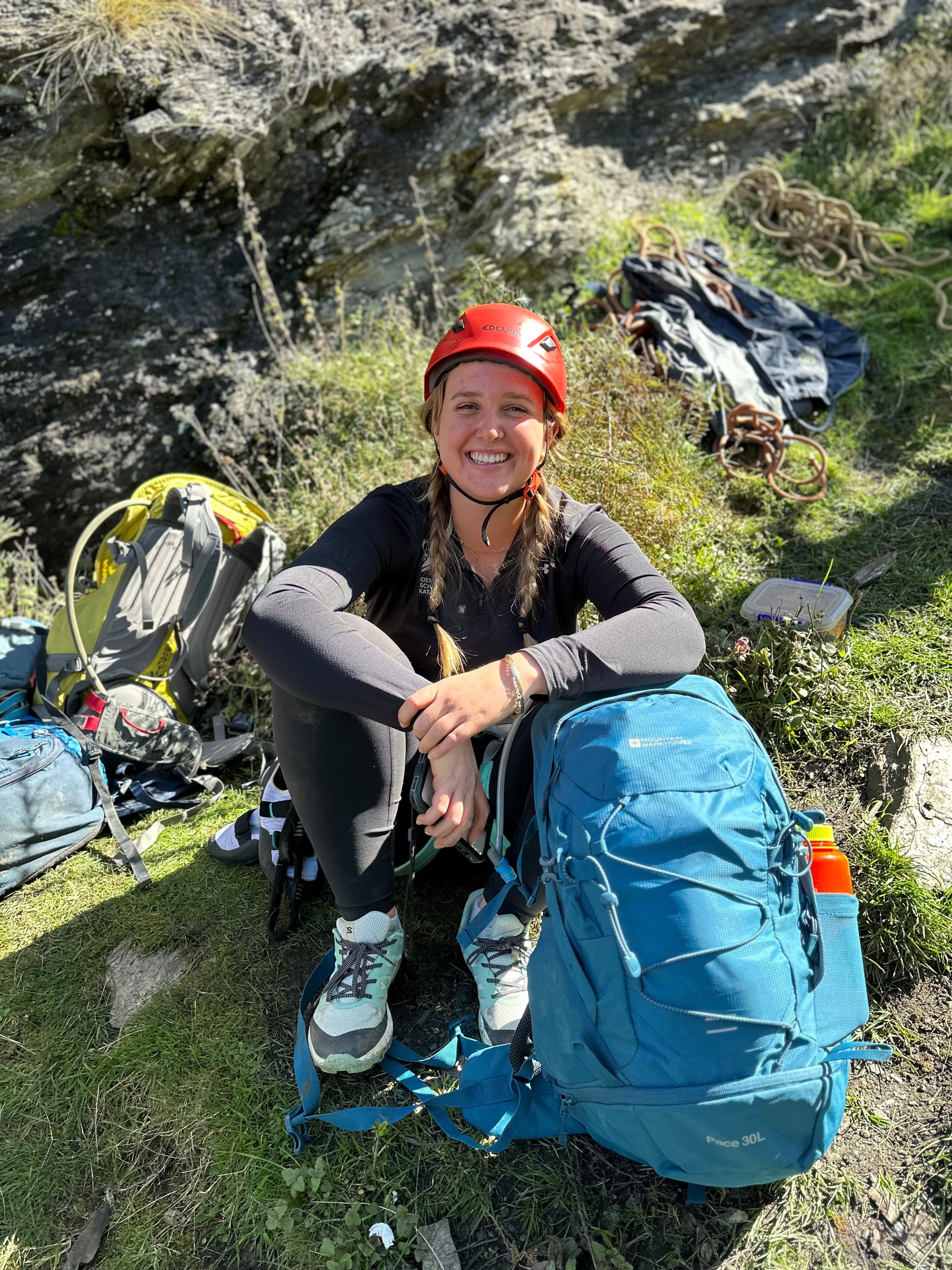 Student sitting at the bottom of a crag happy to have completed their climb