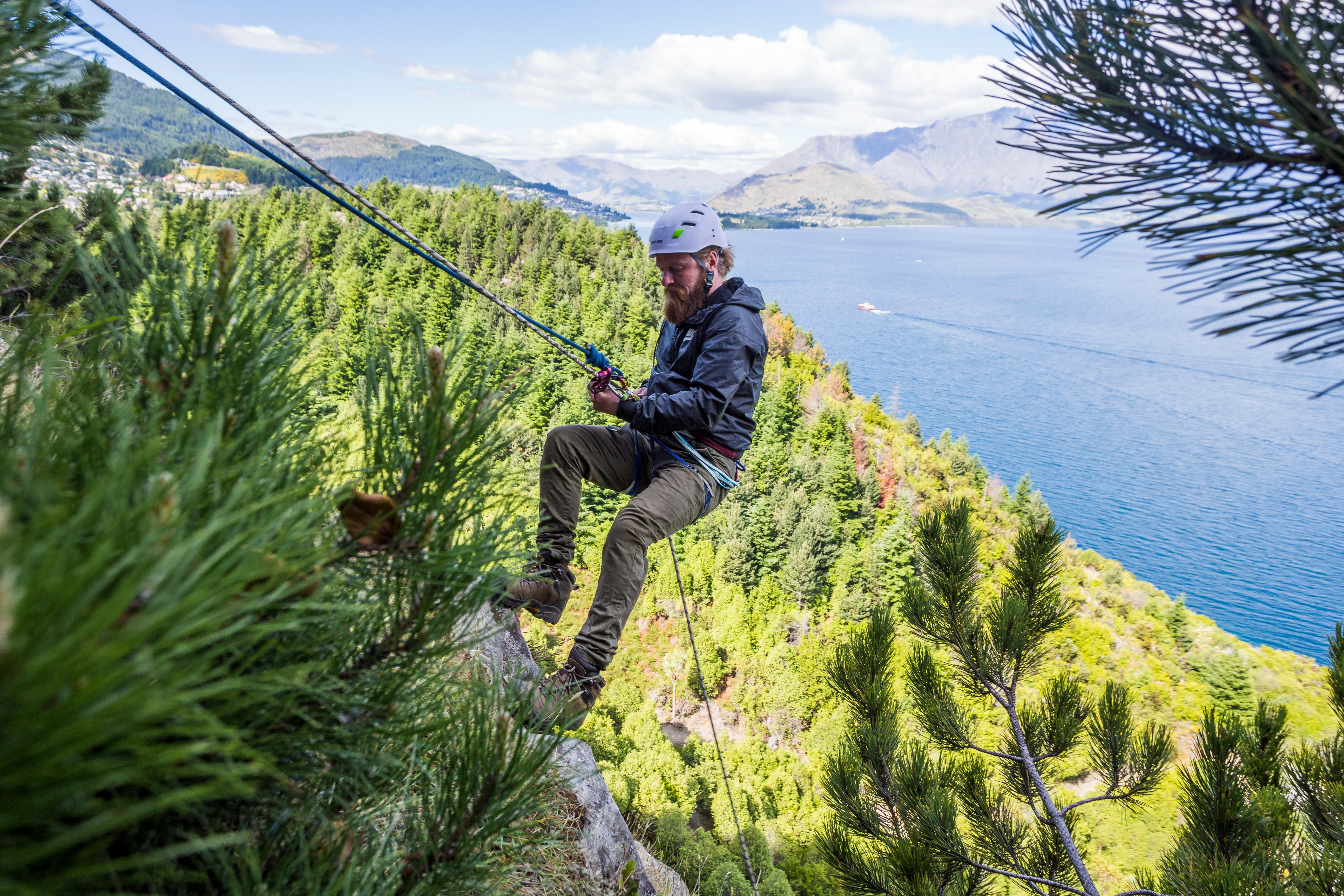 Expert male rock climber abseiling down a rock face in Queenstown