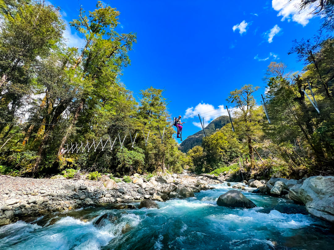 A student crossing a wire bridge while hiking the Routeburn Track in New Zealand