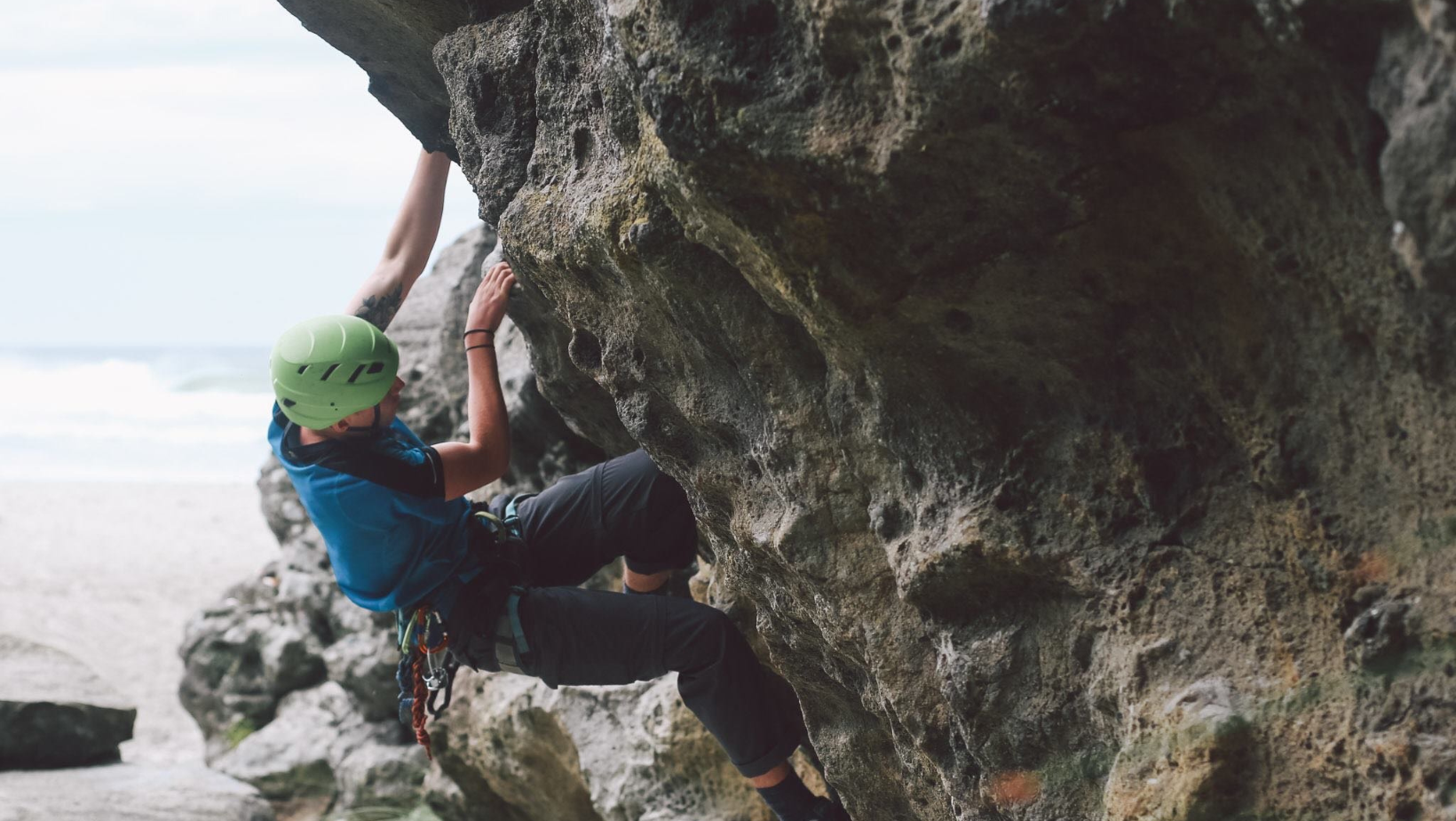 Male rock climbing on a coastal crag in Dunedin New Zealand